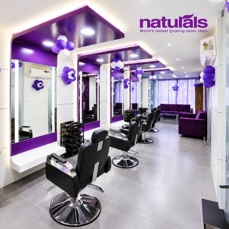 Modern Naturals salon interior with purple styling stations, salon chairs, mirrors, and bright contemporary lighting.
